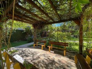 zwei Bänke unter einer Pergola im Garten in der Unterkunft Apartamento Vista do Quilombo 2 dorm by Achei Gramado in Gramado