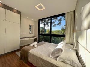 1 dormitorio con cama y ventana grande en Incrível Casa Araucária 3 Suítes by Achei, en Canela