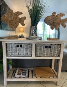 a console table with wicker baskets and two fish on top at Bright and Beachy 2Bed 1Bath Home - Unit 210 in Cocoa Beach