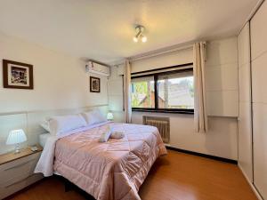 Habitación pequeña con cama y ventana en Casa Allegro 3dorm prox Lago Negro by AcheiGramado, en Gramado
