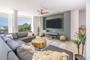 a living room with a gray couch and a tv at The one and only Pedregal Hollywood House in Cabo San Lucas