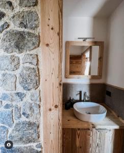 a bathroom with a sink and a stone wall at Atelier della Montagna in Zambla Alta
