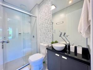 y baño con aseo, lavabo y ducha. en Apartamento Aire 1 dorm by Achei Gramado, en Gramado