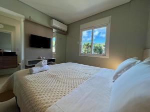 1 dormitorio con 1 cama blanca grande y ventana en Apartamento Res Aire 2 dorm by Achei Gramado, en Gramado