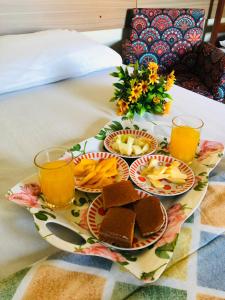a tray of food on a bed with glasses of orange juice at POUSADA EVELINA in Foz do Iguaçu