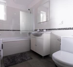 a white bathroom with a sink and a toilet at The Nook Apartment - only 15 mins to Poiana Brasov in Râşnov