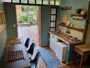 uma cozinha com uma mesa e cadeiras e uma cozinha com uma janela em CASA DE CHICO - Tiny House em Guarda do Embaú