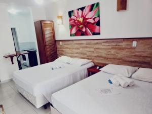 a hotel room with two beds and a painting on the wall at Pousada Bem Viver in Ubatuba +71 photos