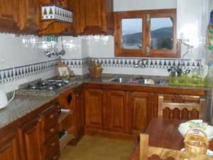 cocina con armarios de madera y horno con fogones en La Villa, Alojamiento Rural en Iznájar