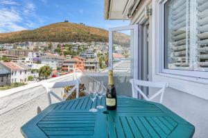 una bottiglia di vino seduta su un tavolo blu sul balcone di Backup-Powered Elegant Promenade Retreat a Città del Capo