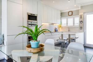 cocina con mesa de cristal y maceta en Backup-Powered Elegant Promenade Retreat, en Ciudad del Cabo