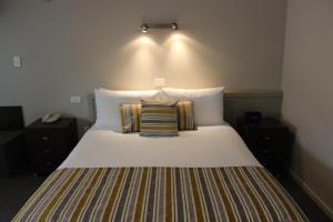 a bed with two pillows on it in a room at Quality Inn Acapulco Taupo in Taupo