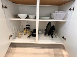 a white pantry with bowls and other kitchen utensils at dyffryn cottage in Blaengawr