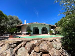 a house with a stone wall in front of it at Casale al mare - villa with swimming pool 150 meters from the beach in Porto Columbu - Perdʼe Sali