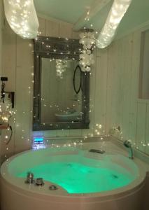 La salle de bains est pourvue d'une baignoire avec de l'eau verte et des lumières. dans l'établissement Appart Aix sauna jacuzzi balneo spa privatifs hyper centre historique cour intérieur, à Aix-en-Provence