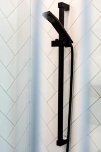 a black shower head hanging on a wall at Le Virtuose - Vieux-Terrebonne in Terrebonne