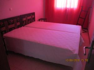 a bedroom with a large white bed with pink lighting at Recanto Verde Cara in Mindelo