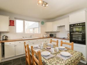a kitchen with a table with chairs and white cabinets at Ambleside in Chard