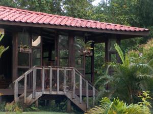 サラピキにあるYatama Rainforest Ecolodgeの木製の階段と赤い屋根の小さな木造家屋