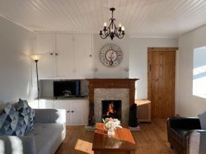 a living room with a fireplace and a clock on the wall at Cottage 433 - Ballyconneely in Ballyconneely