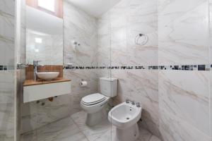 a white bathroom with a toilet and a sink at Soho Village in Villa Carlos Paz