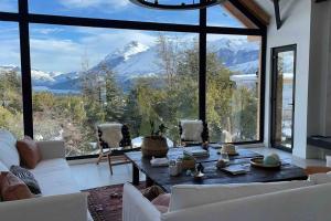 a living room with a table and a large window at Imponente casa en Arelauquen Golf & Country Club in San Carlos de Bariloche
