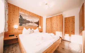 een groot wit bed in een kamer met houten wanden bij Posers Bergwelt in Schladming