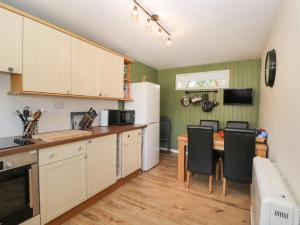 eine Küche mit weißen Schränken sowie einem Tisch und Stühlen in der Unterkunft Orchard House Cottage in Malmesbury