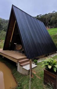 een grote tent met een zwart dak en een houten terras bij Cabana A frame Paraíso nas Montanhas in Marechal Floriano