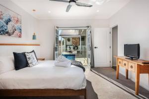 a bedroom with a bed and a desk with a television at McG Mudgee a Hamptons inspired home in Mudgee
