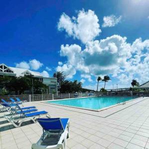 una piscina con sillas azules y un cielo azul en Love Spot Appartement en Baie Nettle