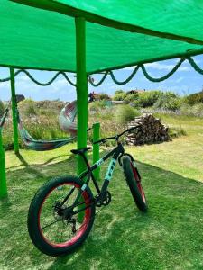 uma bicicleta estacionada sob um dossel verde na relva em Green House Hostel em Cabo Polonio
