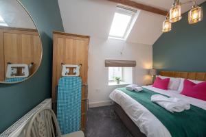ein Schlafzimmer mit einem großen Bett mit rosa und grüner Bettwäsche in der Unterkunft Ollerenshaw Cottage in Buxton