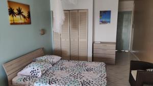 ein Schlafzimmer mit einem Bett und einer Kommode darin in der Unterkunft Résidence Frangipaniers in Sainte-Anne