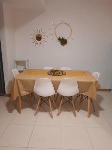 uma mesa de madeira com cadeiras brancas num quarto em vila verde twonhouse T54 em Santa Maria