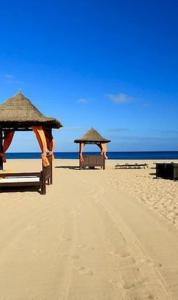 - deux parasols sur une plage de sable avec l'océan dans l'établissement vila verde twonhouse T54, à Santa Maria