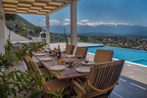 a dining table on a patio with a view of the mountains at Villa Cassandra - A breathtaking view of Souda-Chania bay and the White Mountains in Kókkinon Khoríon