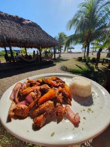 a plate of food with meat and carrots on a beach at Surfing Turtle Lodge in Poneloya