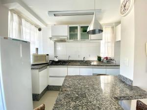 cocina con armarios blancos y encimera de granito en Loft em Bombas - Excelente Localização - 1 dorm 3 pessoas, en Bombinhas