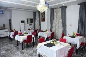 a restaurant with white tables and red chairs and a chandelier at Unic Suites & Hotel in Mbieri