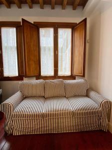 a couch sitting in a living room with windows at Duplex Toledo Catedral con parking gratis in Toledo
