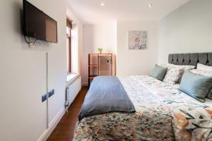 a bedroom with a bed and a flat screen tv at The Old Bakery - Norfolk Holiday Properties in Great Yarmouth