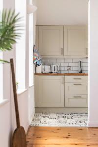 a kitchen with white cabinets and a wooden floor at The Old Bakery - Norfolk Holiday Properties in Great Yarmouth