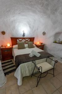 um quarto com uma cama grande e uma cadeira em Casa cueva con encanto em Terque