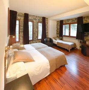 a bedroom with a large white bed and two windows at Hotel Amoretes in La Molina