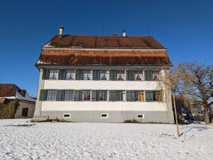 un gran edificio blanco con techo en la nieve en Schloessli Herrenhof, 