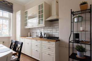 グダニスクにあるOlives Marina Apartment Gdańskの白いキャビネット、テーブルと椅子付きのキッチンが備わります。