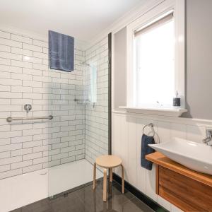 a white bathroom with a sink and a stool at Harrison House in Strahan