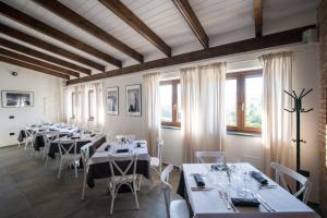 un ristorante con tavoli e sedie bianchi e finestre di Parva Vinea Agriturismo a Benevento