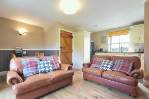 a living room with two leather couches and a kitchen at Chaffinch in Lucker